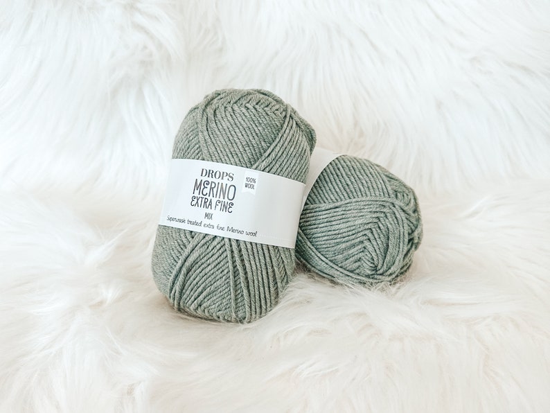 May include: Two balls of green yarn labeled "DROPS MERINO EXTRA FINE MIX 100% WOOL Superwash treated extra fine Merino wool"