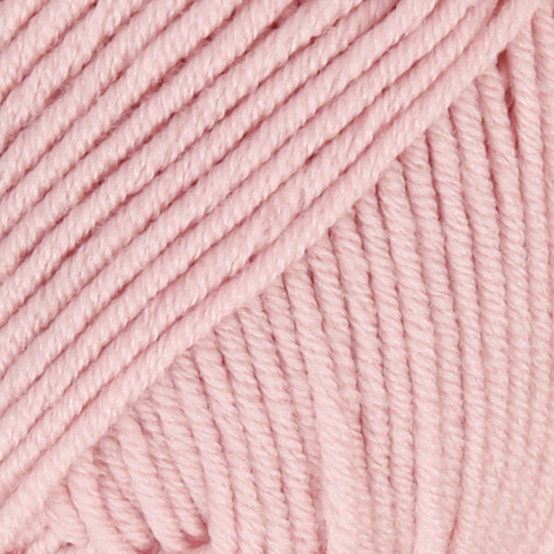May include: Close-up of a soft, pink yarn ball. The yarn is made of a smooth, cotton-like material and is perfect for knitting or crocheting.