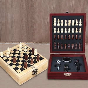 Puede incluir: Un juego de ajedrez de madera con un tablero de ajedrez rojo y negro y una caja de madera que contiene un abridor de botellas, un tapón de botella y un abridor de anillos. El juego de ajedrez está en una caja de madera con un pestillo.