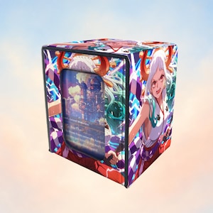 Puede incluir: Una caja para barajas rectangular con una vibrante ilustración estilo anime de un personaje con cabello blanco, cuernos rojos y una prenda superior blanca sin mangas. La caja tiene una ventana frontal que muestra una carta coleccionable.