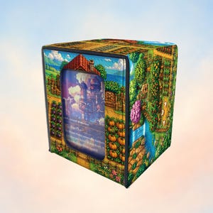 May include: A square deck box featuring a vibrant pixel art landscape with a farm, pumpkin patches, and a house. The front panel has a clear window displaying a trading card with text. The design includes green fields, trees, and a blue sky.