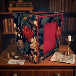 May include: A decorative box with a floral pattern in dark blue, red, and cream. The box has a red interior and is trimmed with red stitching. It sits on a wooden table with a map, a candle, and antique timepieces.