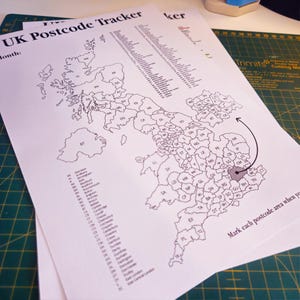 May include: A black and white map of the United Kingdom with the text "UK Postcode Tracker" and "Month:" at the top. The map is divided into regions with their corresponding postcode abbreviations. The map includes an arrow pointing to the London area with the text "Mark each postcode area when you" at the bottom.