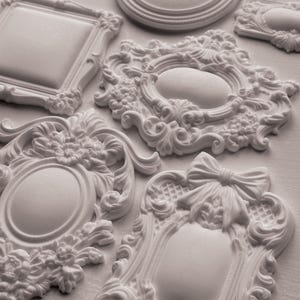 Pode incluir: Uma variedade de molduras decorativas brancas e ornamentadas em várias formas e tamanhos. As molduras apresentam detalhes de volutas, desenhos florais e um laço. Algumas molduras são ovais, redondas e retangulares. Medidas em centímetros.