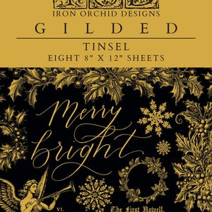 May include: A gold foil sheet with a black background featuring a Christmas-themed design. The design includes a holly wreath, snowflakes, and the words "Merry Bright". The sheet is part of the Iron Orchid Designs Gilded Tinsel collection and includes eight 8-inch by 12-inch sheets.