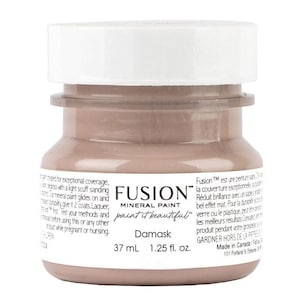 May include: A small glass jar of Fusion Mineral Paint in the color Damask. The jar is labeled with the brand name, the paint color, and the volume in milliliters and fluid ounces. The paint is a light brown color.