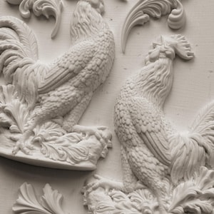 Puede incluir: Esculturas de gallos de yeso blanco con texturas detalladas de plumas y colas. Los gallos están montados sobre bases decorativas con detalles de hojas. También hay varios elementos de yeso en forma de hoja adicionales.