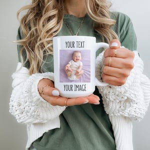 K&ouml;nnte beinhalten: Wei&szlig;e Keramik-Tasse mit individuellem Foto und Text. Die Tasse zeigt ein rechteckiges Bild eines Babys auf lila Hintergrund, mit dem Text "YOUR TEXT" dar&uuml;ber und "YOUR IMAGE" unter dem Foto. Die Tasse wird von einer Person gehalten.