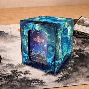 May include: A blue card storage box with a fantasy art design. The box features a cat illustration and a window showing a card. The box is on a playmat with a landscape design.