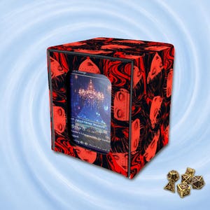 May include: A square card storage box featuring a repeating red and black graphic pattern of stylised faces. The front panel has a clear window displaying a game card with text including "Island Swamp Mountain" and "Lander's Lounge". Five gold dice sit nearby.