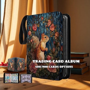May include: A black trading card album with a zipper closure and a black handle. The album features a colorful illustration of a squirrel surrounded by roses. The text "TRADING CARD ALBUM" and "400/900 CARDS OPTIONS" are also visible.