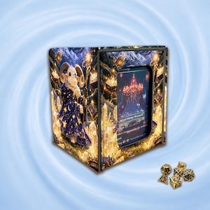 May include: A rectangular deck box featuring a fantasy illustration of a ram in a star-patterned robe holding a staff, with a clear window displaying a trading card. Beside the box are several gold-coloured polyhedral dice with black numbering.