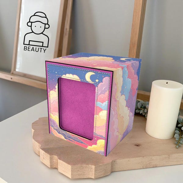 Può includere: Una scatola decorativa con un vivace design di nuvole e luna nei toni del rosa, viola e giallo. La scatola ha un'apertura rettangolare con un interno rosa. La parola "BEAUTY" è stampata su un'immagine vicina.