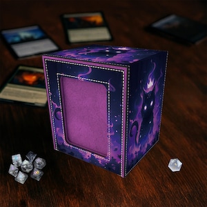 Peut inclure: Boîte de rangement pour cartes de couleur bleu marine et violet, avec un motif de silhouette de chat. L'intérieur de la boîte est violet et bordé de coutures blanches. Des dés et des cartes à collectionner sont visibles.