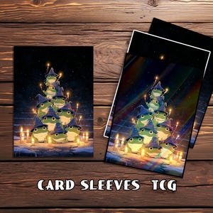 Op de afbeelding: Kaarthoezen met een fantasie-illustratie van groene kikkers met blauwe tovenaars hoeden, gerangschikt in een piramidevorm, met kaarsen en een nachthemel achtergrond. De tekst "CARD SLEEVES TCG" staat onderaan.