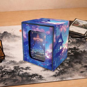 May include: A square card storage box with a vibrant, colorful design featuring a fantasy landscape with a castle. The box has a clear window displaying a card. The box is on a playmat with a landscape design.