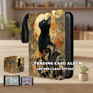 May include: Black trading card album with a black cat illustration, surrounded by orange flowers and a golden background. The album has a black handle and the text "TRADING CARD ALBUM 400/900 CARDS OPTIONS".