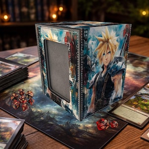 Puede incluir: Caja de almacenamiento de cartas en forma de cubo con una ilustración en acuarela de un personaje con pelo rubio puntiagudo y una espada. La caja tiene un interior gris y costuras blancas. Dados rojos y cartas sobre la mesa.