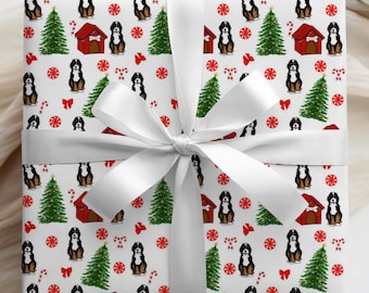 May include: A wrapped gift with white paper featuring a repeating pattern of Bernese Mountain Dogs, Christmas trees, red dog houses, candy canes, and bows. The gift is tied with a large white satin ribbon and bow.