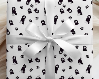 May include: A wrapped gift with white paper featuring a pattern of black and white dogs and paw prints. The gift is tied with a white satin ribbon and bow. The overall theme is a dog lover's gift.