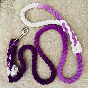 May include: A purple and white ombre rope dog leash with a silver clip. The leash is made of thick, braided rope and has a soft, fuzzy texture.