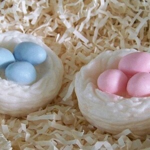 Op de afbeelding: Twee witte nesten met elk drie zeep-eieren. E&eacute;n nest heeft blauwe eieren en het andere heeft roze eieren.