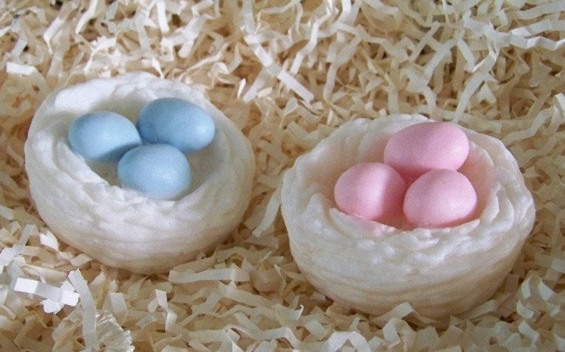 Op de afbeelding: Twee witte nesten met elk drie zeep-eieren. E&eacute;n nest heeft blauwe eieren en het andere heeft roze eieren.