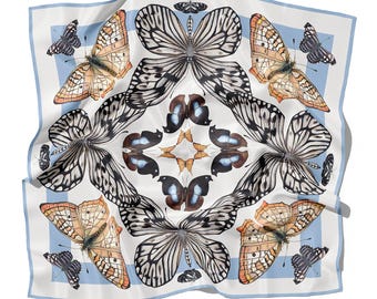May include: Square silk scarf with a butterfly pattern. The scarf features a white background with a light blue border. The butterflies are in shades of black, brown, and orange. The scarf is a square shape.