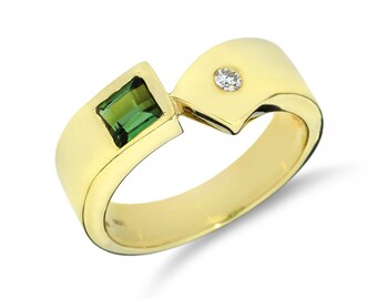May include: A gold ring with a green gemstone and a small diamond. The ring has a unique, asymmetrical design.