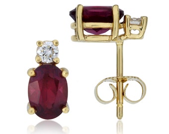 May include: A pair of gold earrings with a red oval gemstone and a smaller round diamond accent. The earrings have a post and butterfly back.