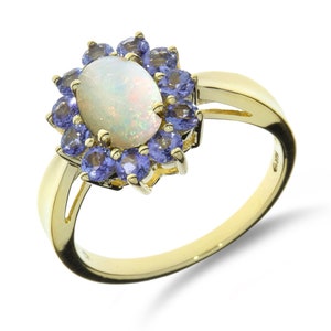 Puede incluir: Un anillo de oro con una gran piedra de ópalo ovalada rodeada por un halo de pequeñas piedras de amatista púrpura.