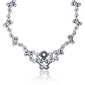 Op de afbeelding: Een zilveren ketting met een delicaat, versierd ontwerp. De ketting heeft een centrale hanger met een rond ontwerp en een kleine, ronde steen in het midden.