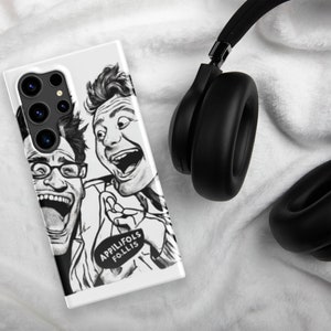 May include: White phone case featuring a black and white illustration of two men with open mouths and surprised expressions. The case has the text "APPILIFOLS F.O.LLIS" on it. Black headphones are in the background.