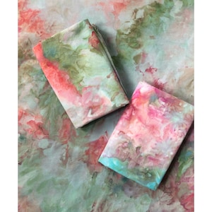 May include: Two fabric squares with a tie-dye pattern in shades of pink, green, and blue. The fabric has a soft, watercolor-like appearance.