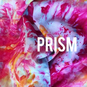 Może przedstawiać: Zbliżenie na r&oacute;żową, niebieską i ż&oacute;łtą tkaninę tie-dye z napisem "PRISM" w białym kolorze. Tekst został stworzony za pomocą czcionki "Font Candy".