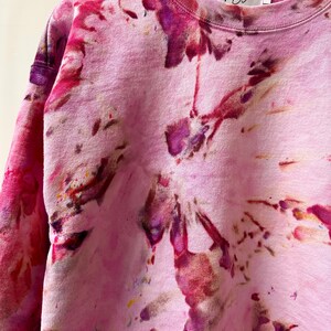 Op de afbeelding: Roze tie-dye sweatshirt met een wit label met de tekst "Anna Joyce" en maat "S".