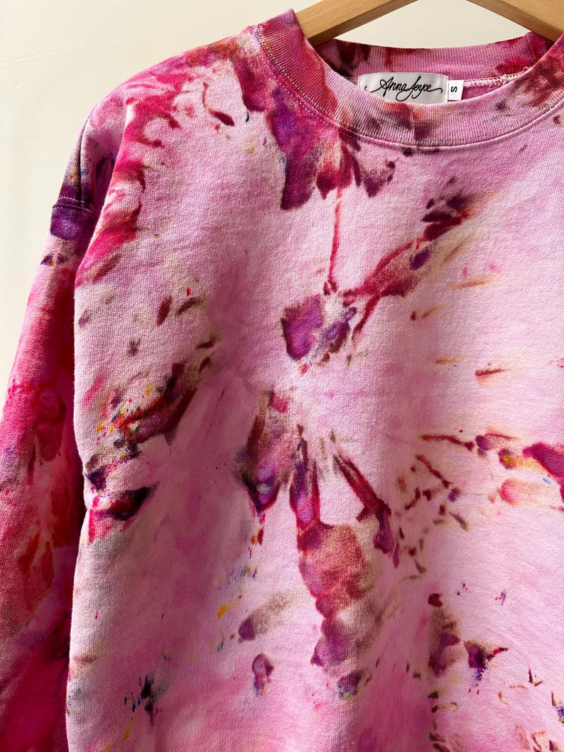 Op de afbeelding: Roze tie-dye sweatshirt met een wit label met de tekst "Anna Joyce" en maat "S".