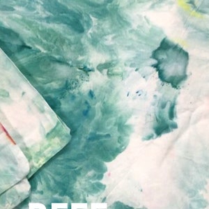 Może przedstawiać: Zbliżenie na tkaninę tie-dye w zielono-białej kolorystyce. Tkanina ma zakręcony wz&oacute;r, a w dolnej części środkowej obrazu nadrukowano białe litery "REEF".
