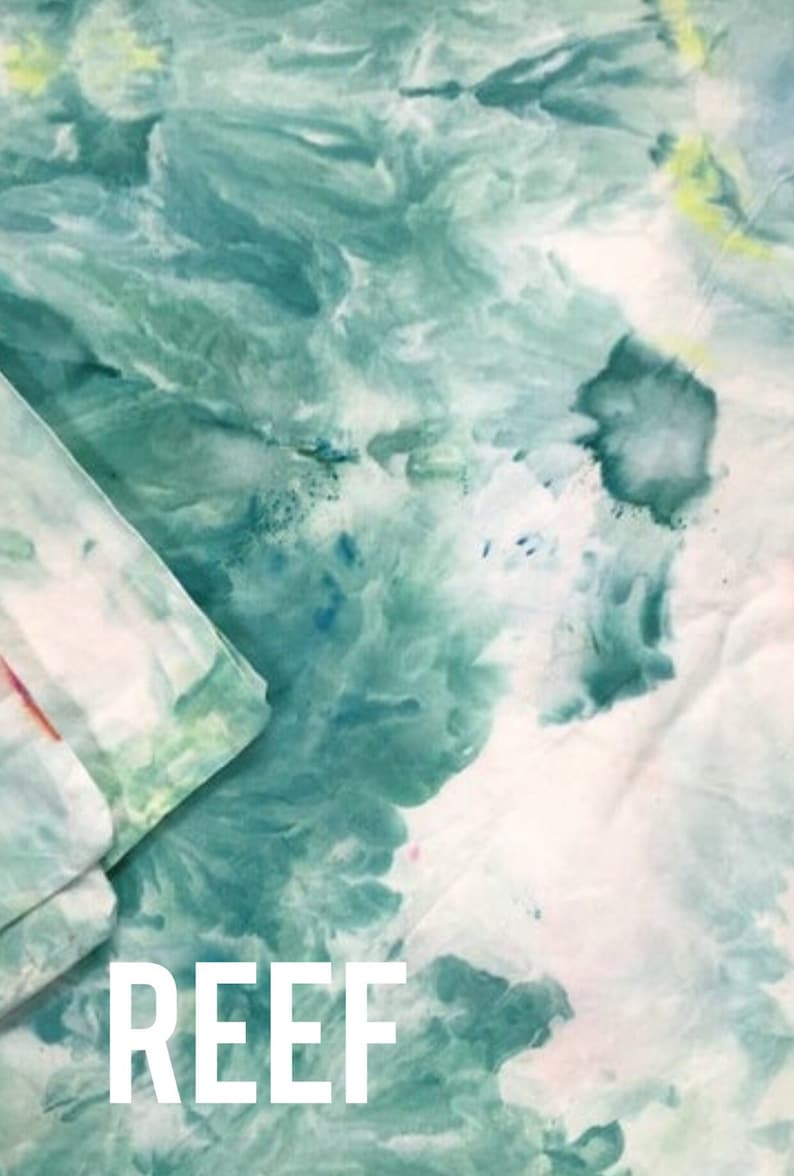 Może przedstawiać: Zbliżenie na tkaninę tie-dye w zielono-białej kolorystyce. Tkanina ma zakręcony wz&oacute;r, a w dolnej części środkowej obrazu nadrukowano białe litery "REEF".