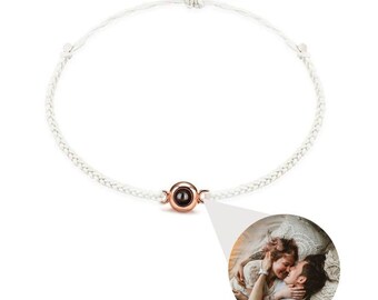 Peut inclure: Bracelet en cordon blanc tressé avec une perle centrale de couleur or rose. La perle contient une image cachée d'un couple. Le bracelet est noué avec des cordons blancs réglables.
