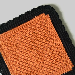 May include: Orange crochet dishcloth with a black crocheted border.