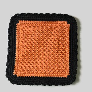 May include: Orange crochet dishcloth with a black crocheted border.