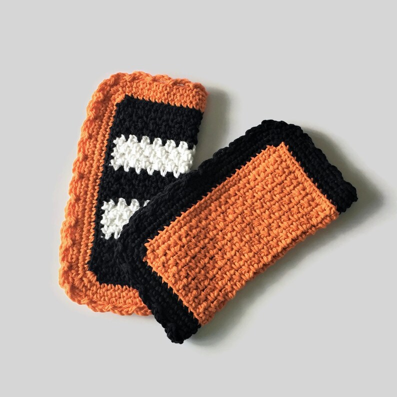 May include: Two crocheted dishcloths, one orange with black trim and one black with white and orange stripes.