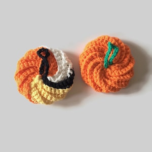 May include: Two crocheted pumpkins, one orange and one with orange, black, white, and yellow stripes.