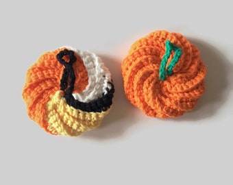 May include: Two crocheted pumpkins, one orange and one with orange, black, white, and yellow stripes.