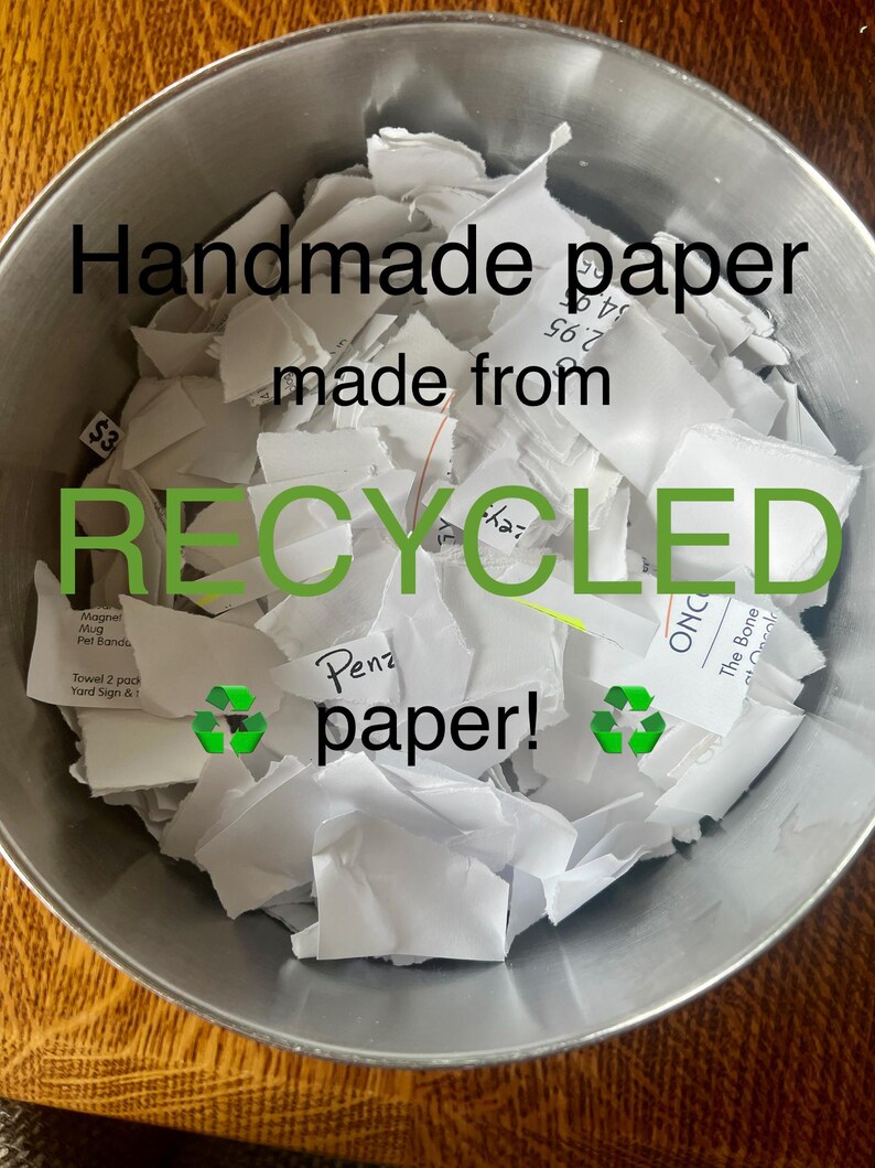 K&ouml;nnte beinhalten: Eine silberne Sch&uuml;ssel gef&uuml;llt mit zerkleinertem wei&szlig;em Papier. Das Papier ist mit den Worten "Handgemachtes Papier aus recyceltem Papier!" beschriftet.