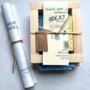 K&ouml;nnte beinhalten: Eine Holzkiste mit einem blauen und wei&szlig;en gemusterten Stoff im Inneren. Die Kiste ist mit "Wooden Deck Great Sources of" beschriftet und enth&auml;lt den Text "Save this twine!" und "Check us out online, make something, do something".