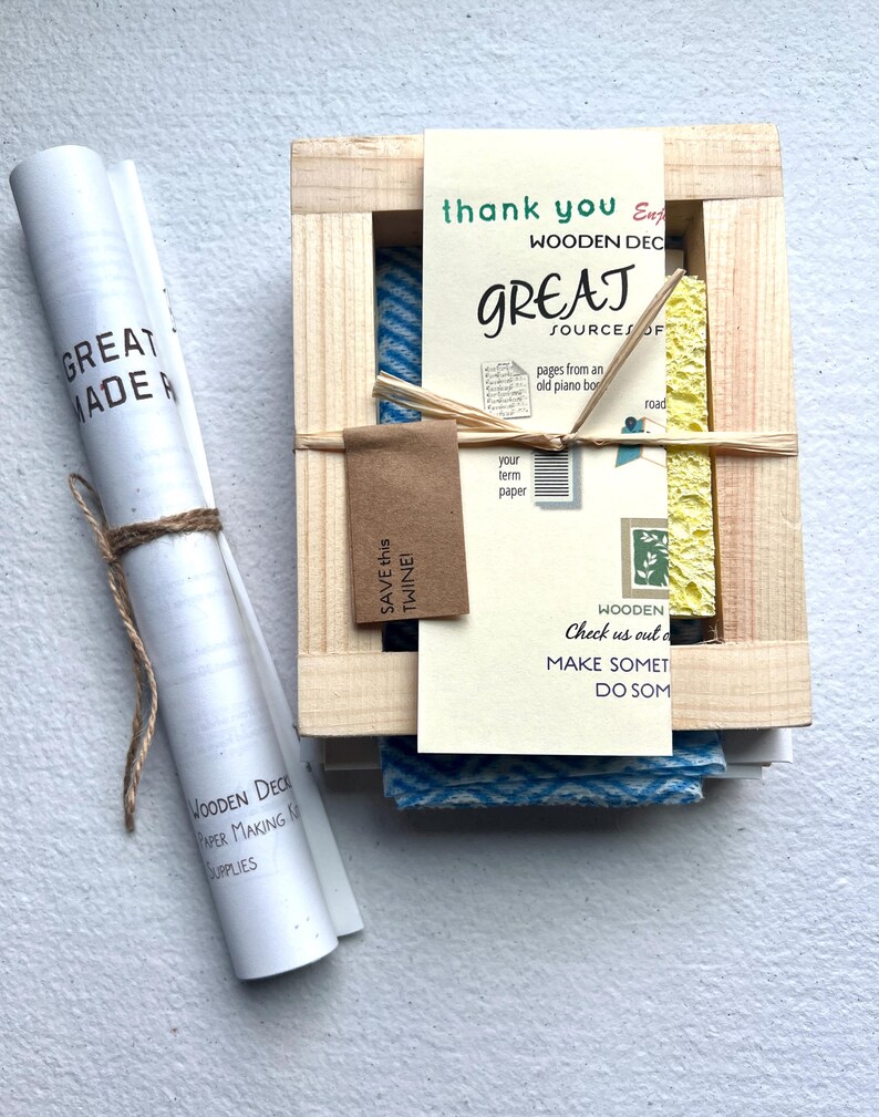 K&ouml;nnte beinhalten: Eine Holzkiste mit einem blauen und wei&szlig;en gemusterten Stoff im Inneren. Die Kiste ist mit "Wooden Deck Great Sources of" beschriftet und enth&auml;lt den Text "Save this twine!" und "Check us out online, make something, do something".