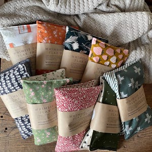 May include: Assortment of 10 flax seed heat packs with various floral and patterned fabric covers. The packs are labeled "Whimsy Flax Packs" and include the shop's Instagram handle.