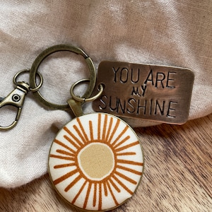May include: A keychain with a sun design and a metal tag that says "You are my sunshine".